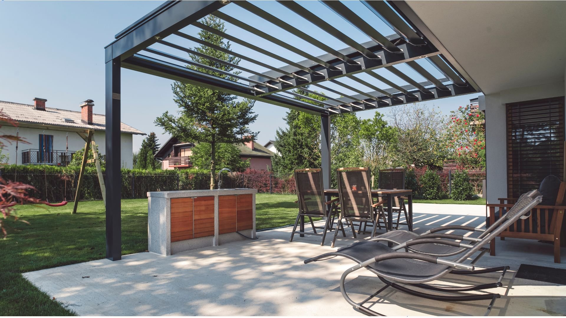Sunlight through a pergola above an outdoor dining area, with a garden beyond