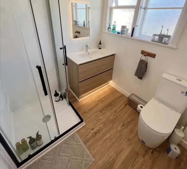 Bathroom with a timber vanity, glass shower and pale wall tiles