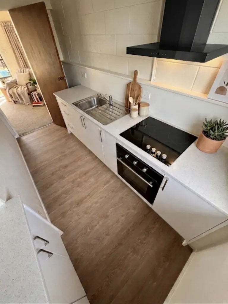Compact kitchen with white cabinetry, pale timber flooring and a tiled splashback