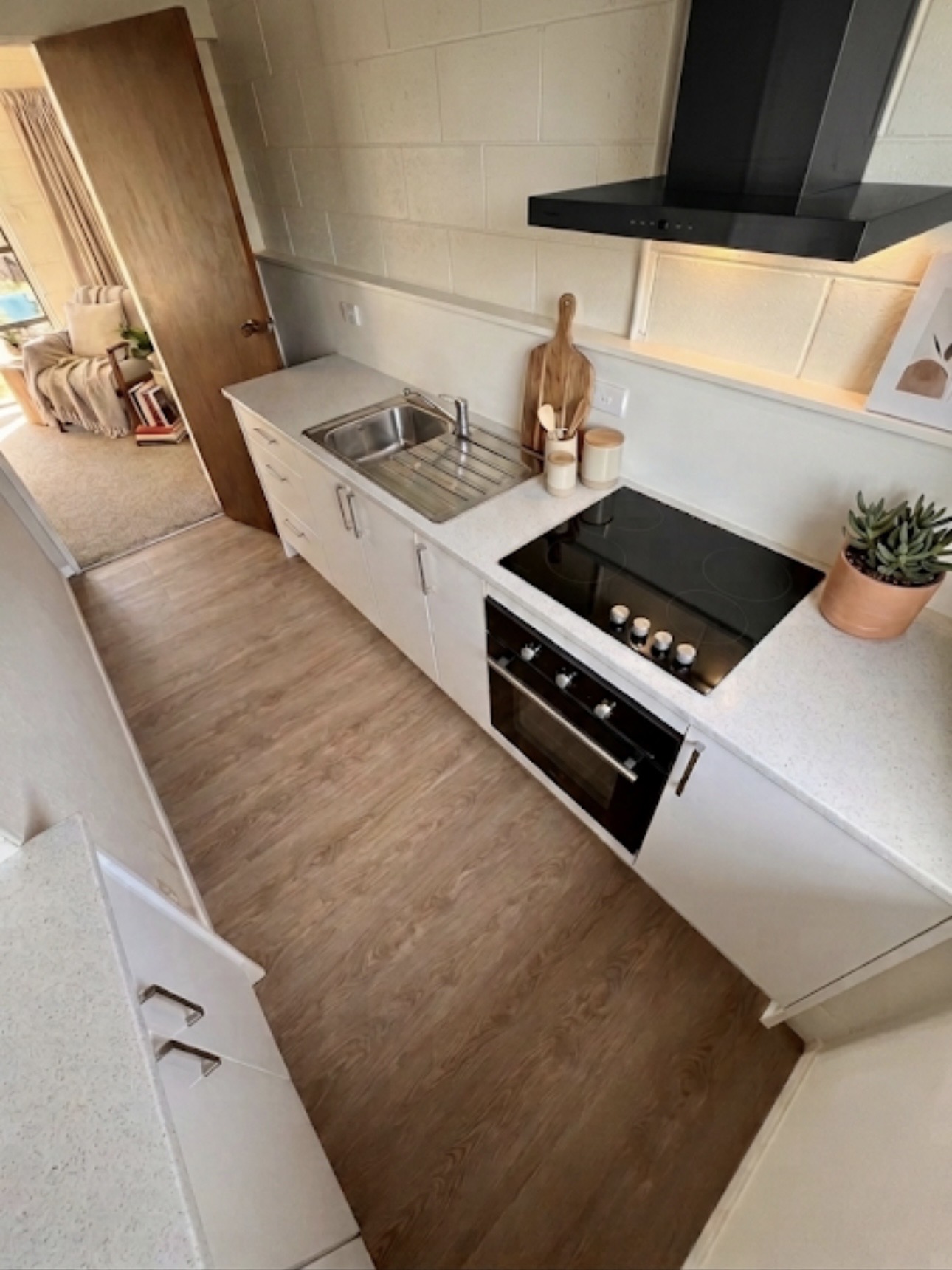 Compact kitchen with white cabinetry, pale timber flooring and a tiled splashback